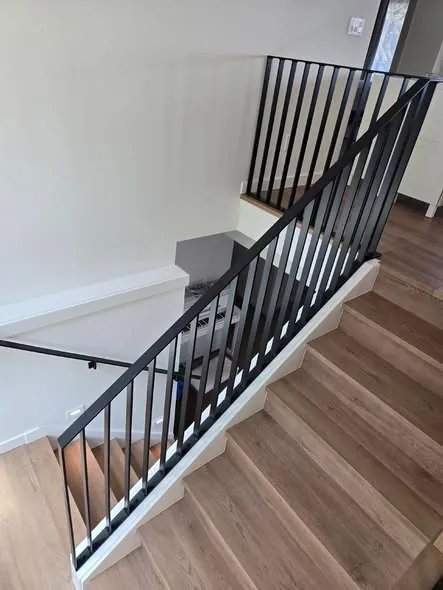 Finished black steel stair railing installed in a home
